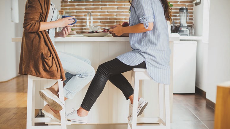 Marketing image showing a couple of friends chatting at a kitchen island 